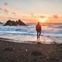 man standing in the waves at sunset | wealthify.com