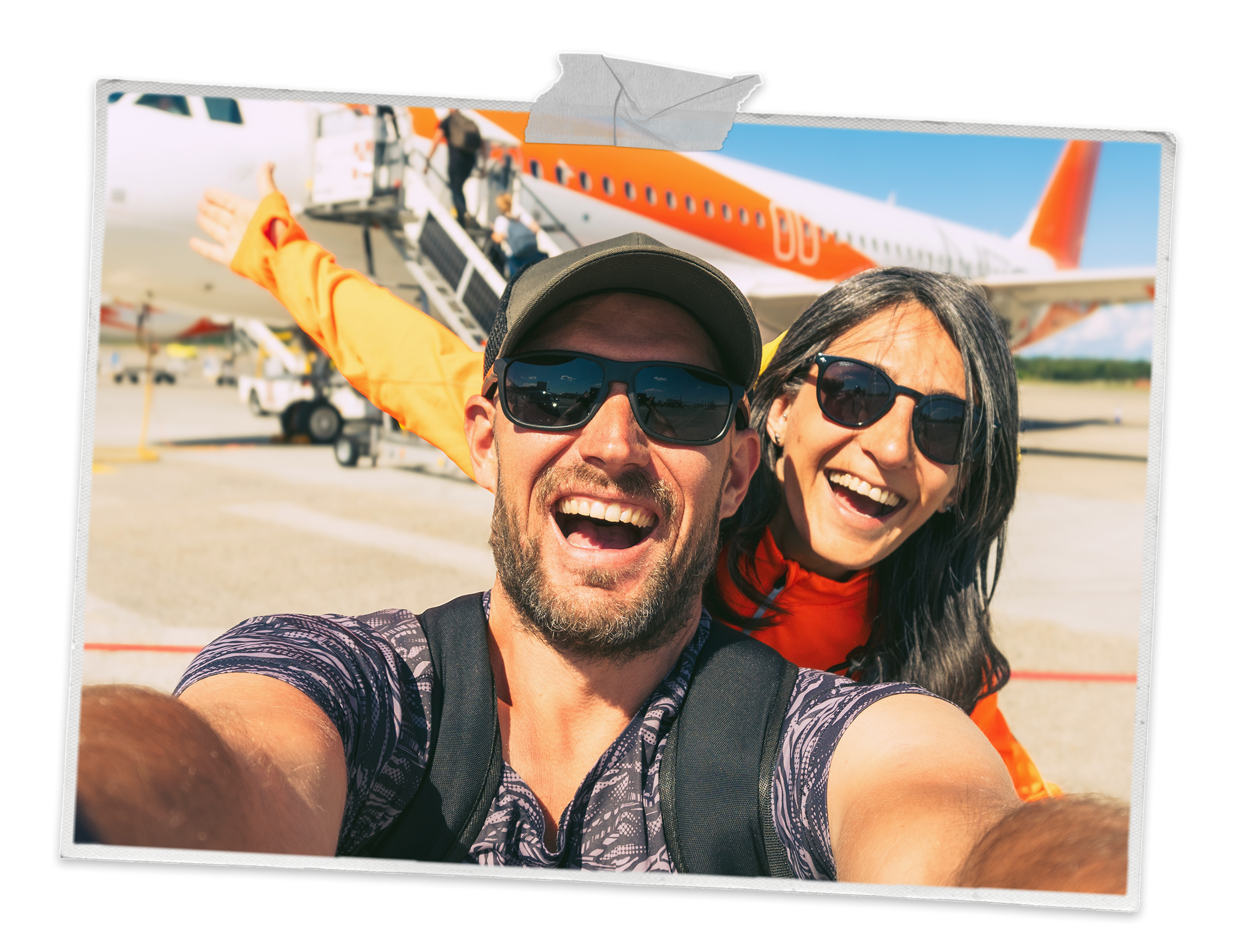 A couple smiling into the camera with a aeroplane behind them