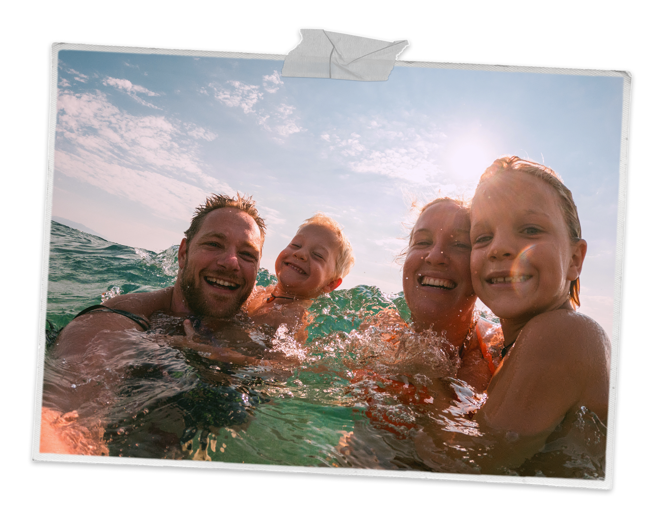 Two children and their parents swimming in the sea and smiling at the camera