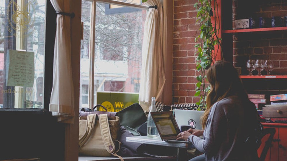 A woman sat in a coffee shop using a laptop.