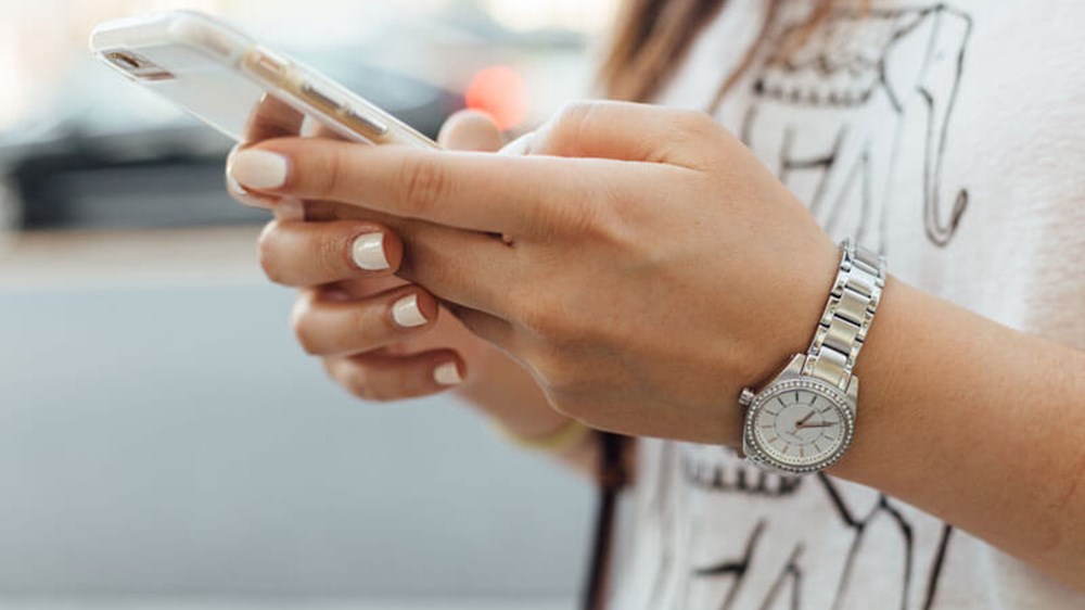 A close up of a woman's hands as she's using a mobile phone