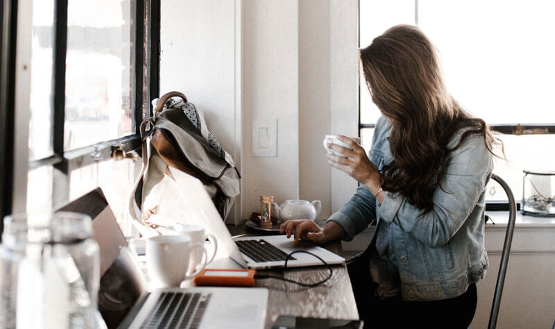 A woman sitting a desk holding a cup of coffee.
