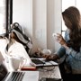 A woman sitting a desk holding a cup of coffee. 