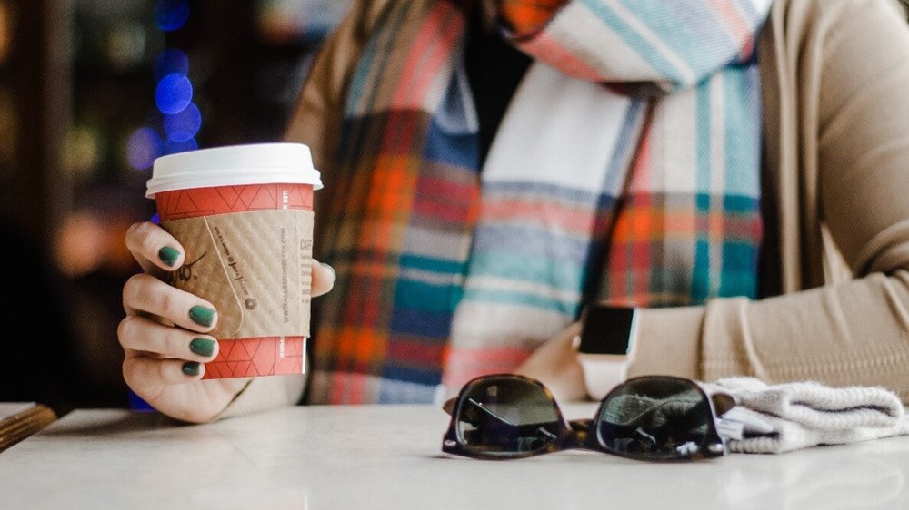 Woman wearing a tartan scarf holding a coffee