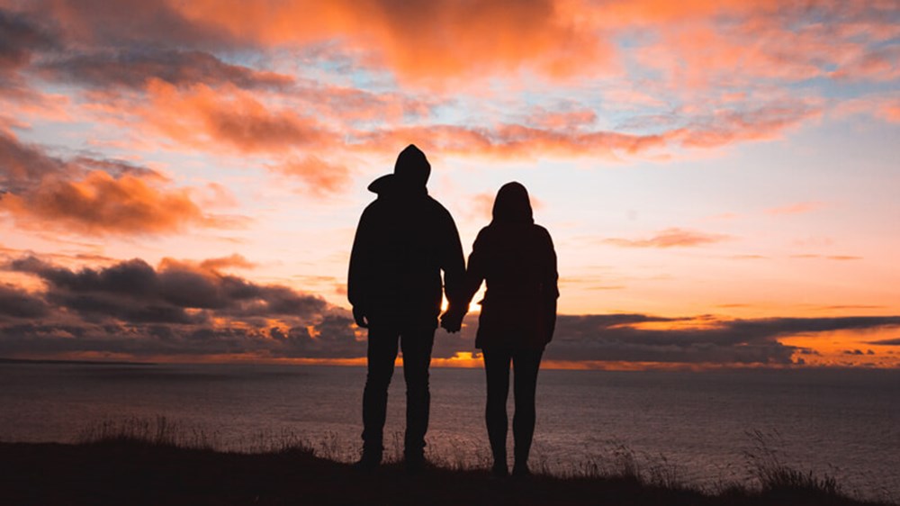 Couple holding hands and looking at the horizon | Wealthify