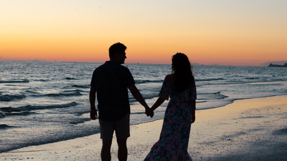 Couple holding hands at the beach | Wealthify