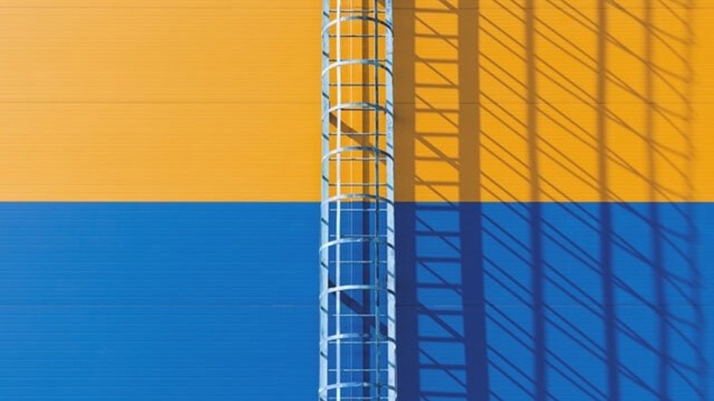 A ladder going up a blue and orange wall | wealthify.com