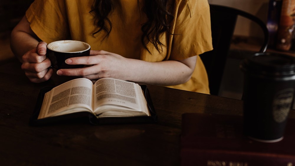 Woman reading book with mug in hand