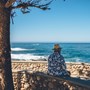 Old man sitting on wall overlooking beach
