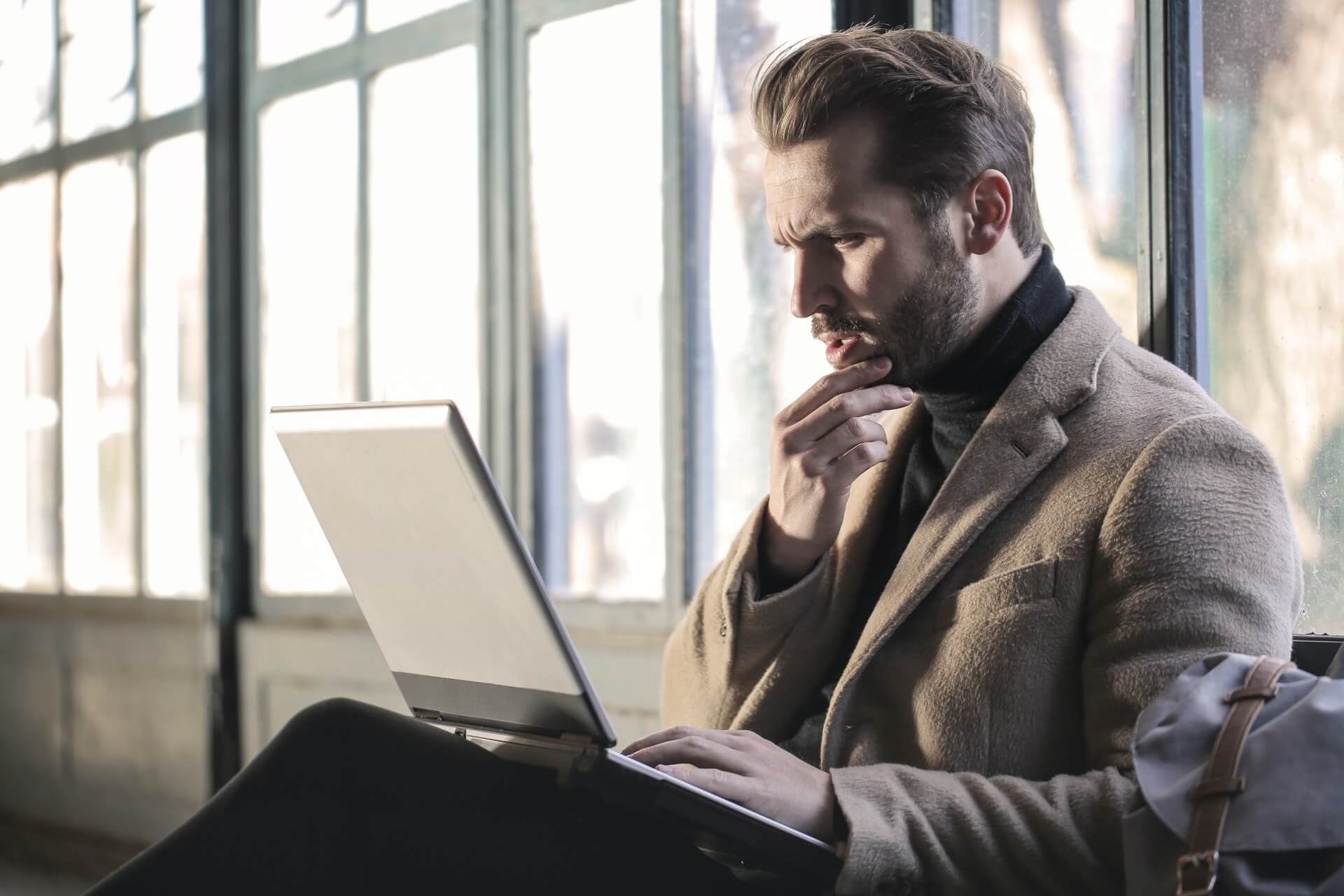 Man looking at laptop with hand on chin