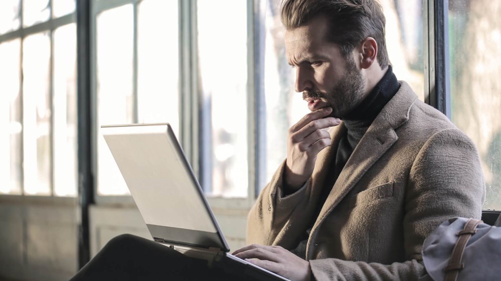 Man looking at laptop with hand on chin