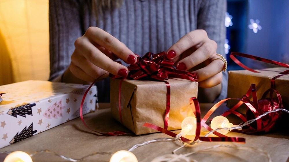 Woman holding a pile of wrapped presents in front her face