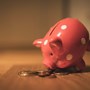 Piggy bank leaning on top of a pile of coins