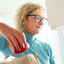 Older women packing away groceries while looking at her phone