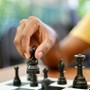 Close up of hand picking up chess piece