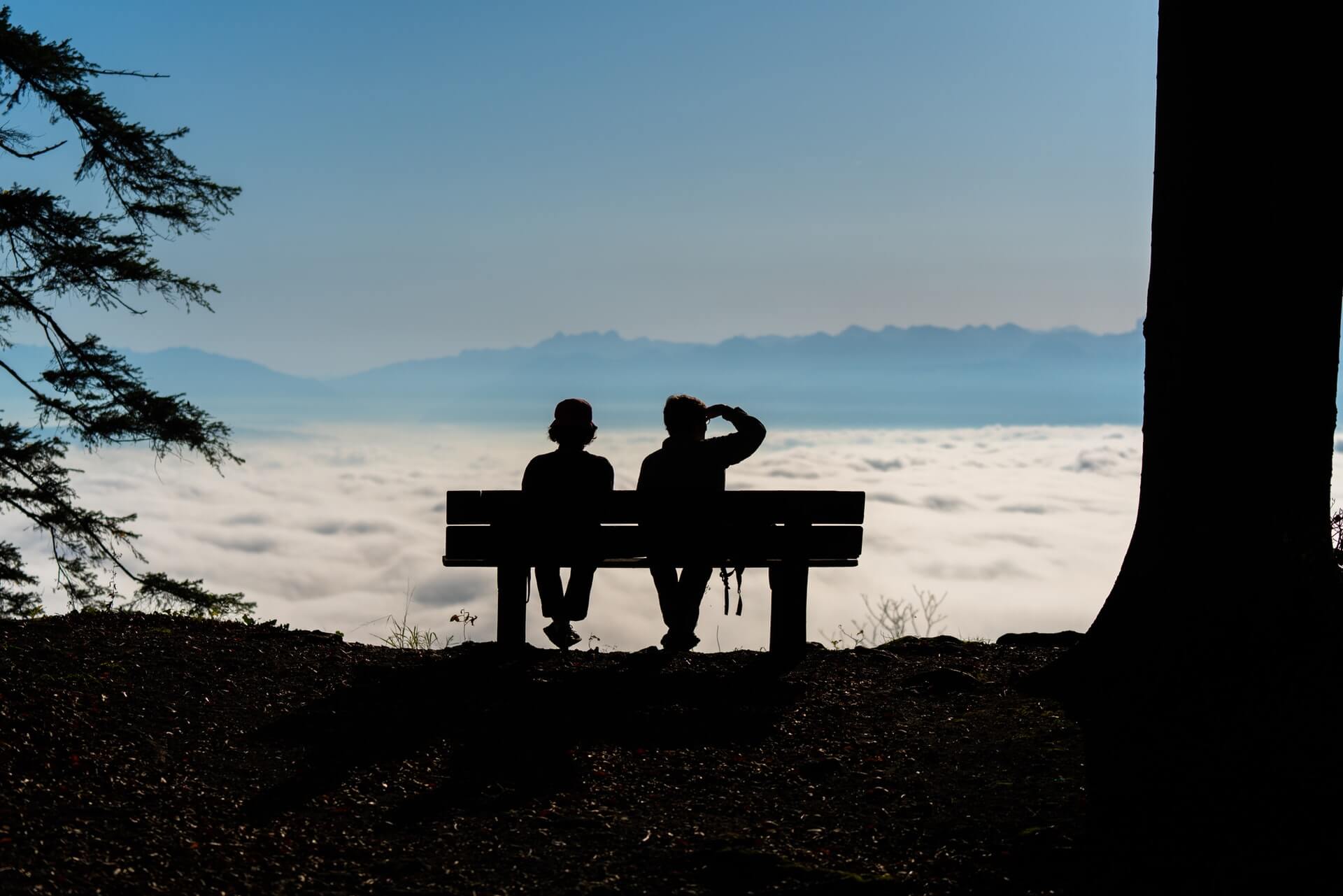 A retired couple sitting on a bench overlooking the sea