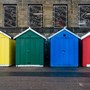 four different coloured sheds standing next to each other - from left to right the sheds are yellow, green, blue and red | wealthify.com