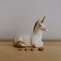 Unicorn money box with pile of coins in front of it