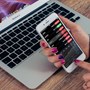 Someone checking stocks on phone with laptop underneath