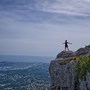 Person holding out their arms on top of a cliff edge
