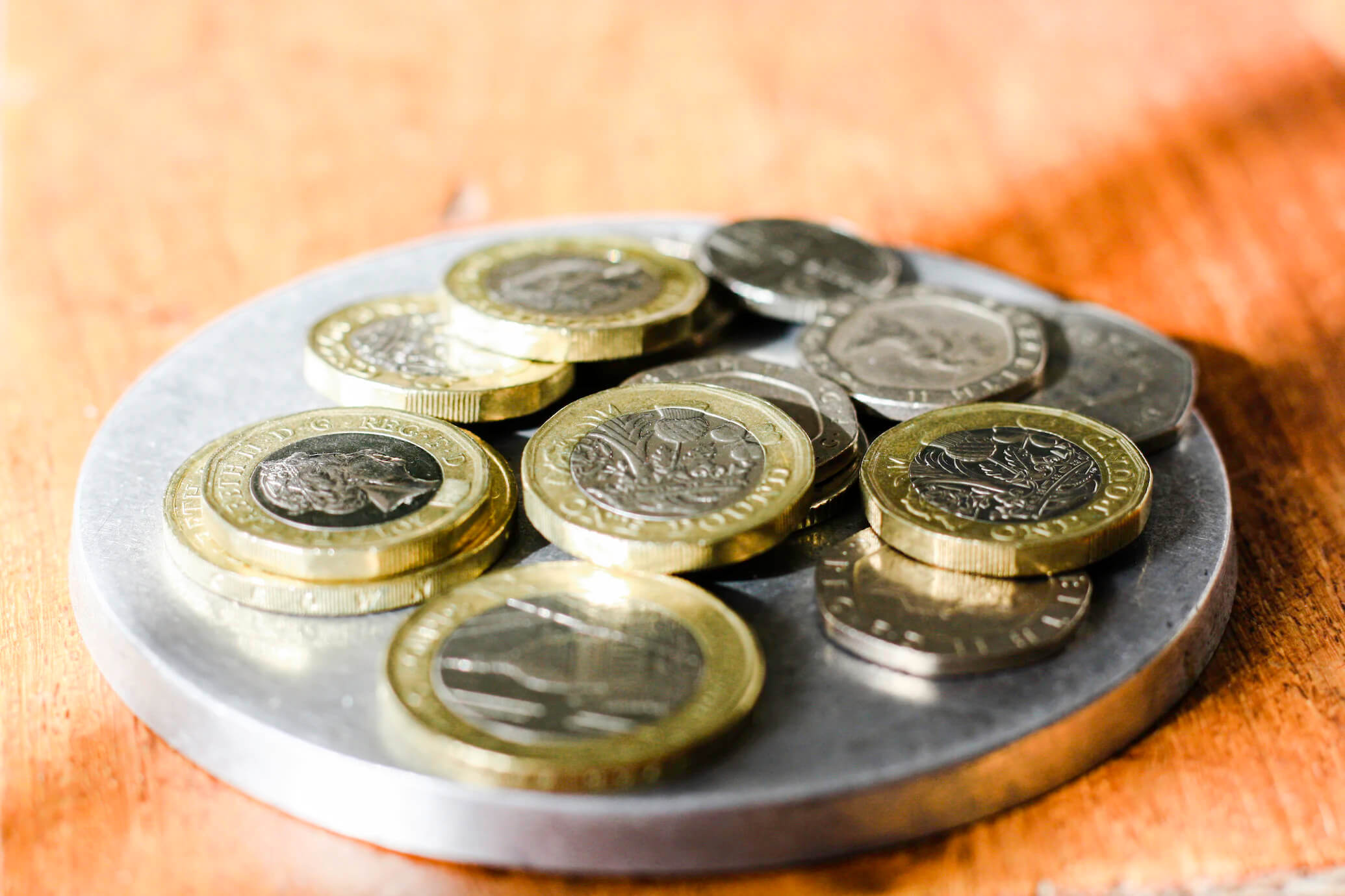 Various money and coins scattered on silver plate