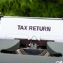Paper sticking out of typewriter with 'tax return' typed on it