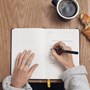 Hand holding pen writing in planner