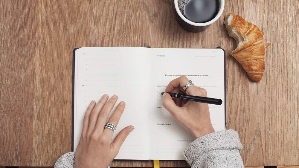 Hand holding pen writing in planner