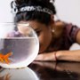 Woman looking into goldfish bowl on a table
