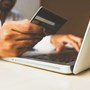 Close up of hands holding debit card and typing on a laptop