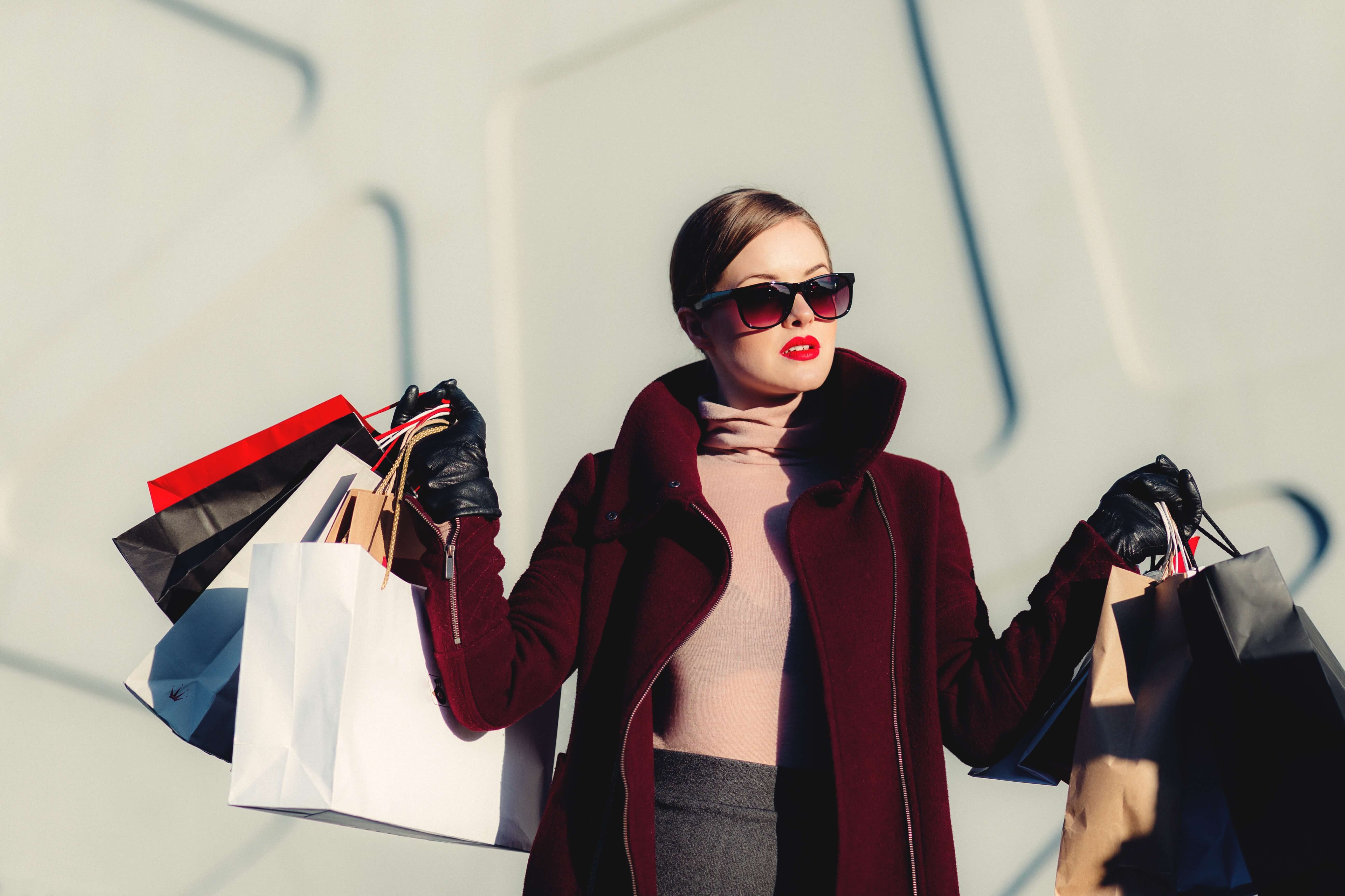 Woman wearing sunglasses holding multiple shopping bags