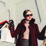 Woman wearing sunglasses holding multiple shopping bags