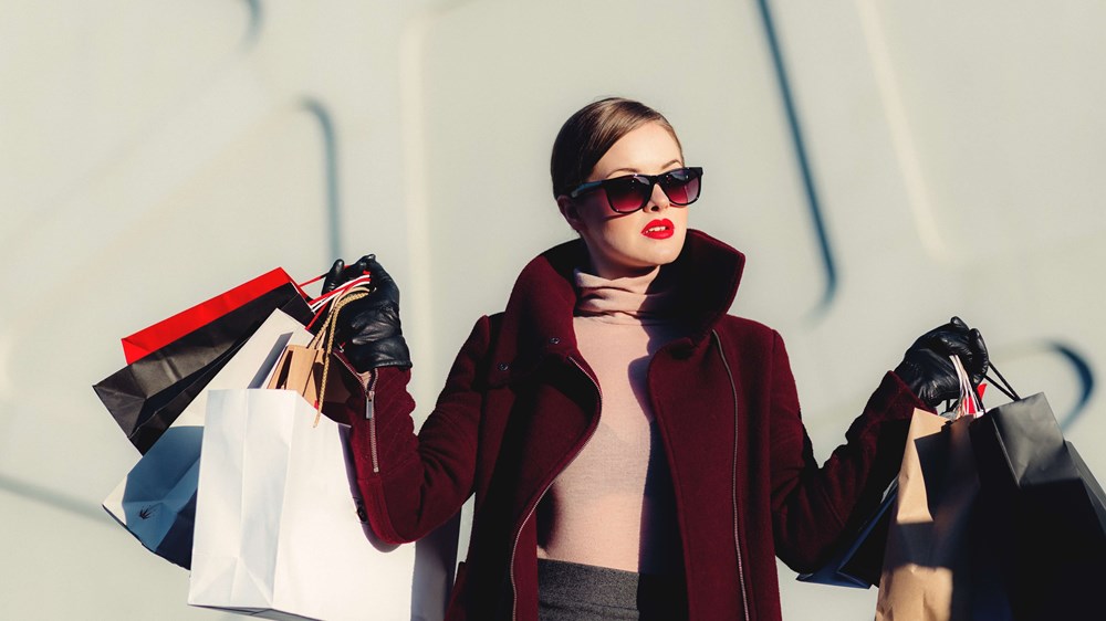 Woman wearing sunglasses holding multiple shopping bags