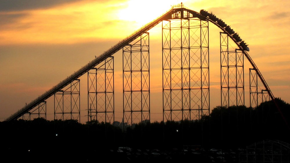 Image of a rollercoaster silhouette against a sunset and yellow sky