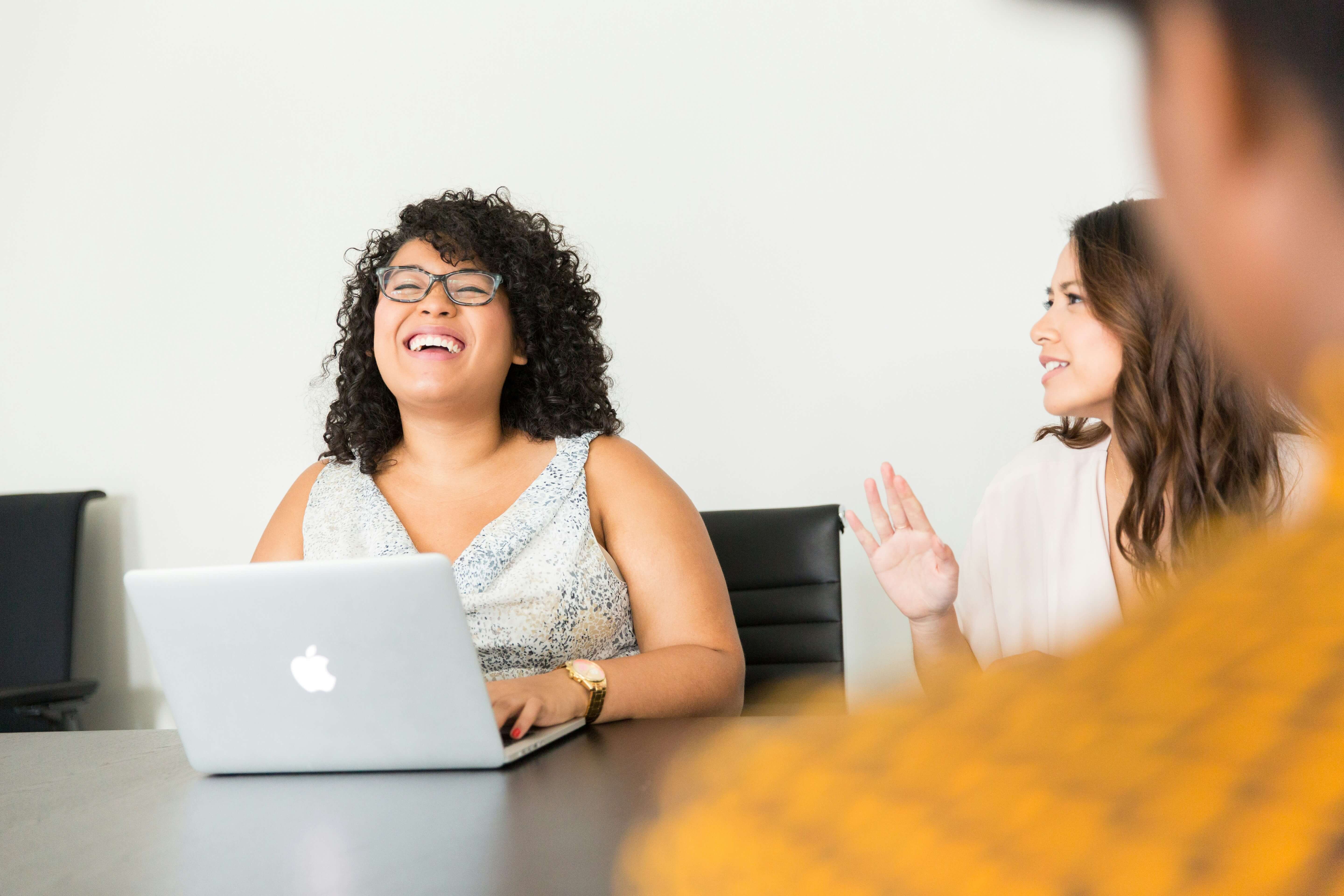 Woman laughing as they work on laptops