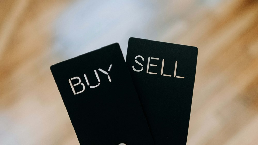 Someone holding buy and sell signs | Weathify.com