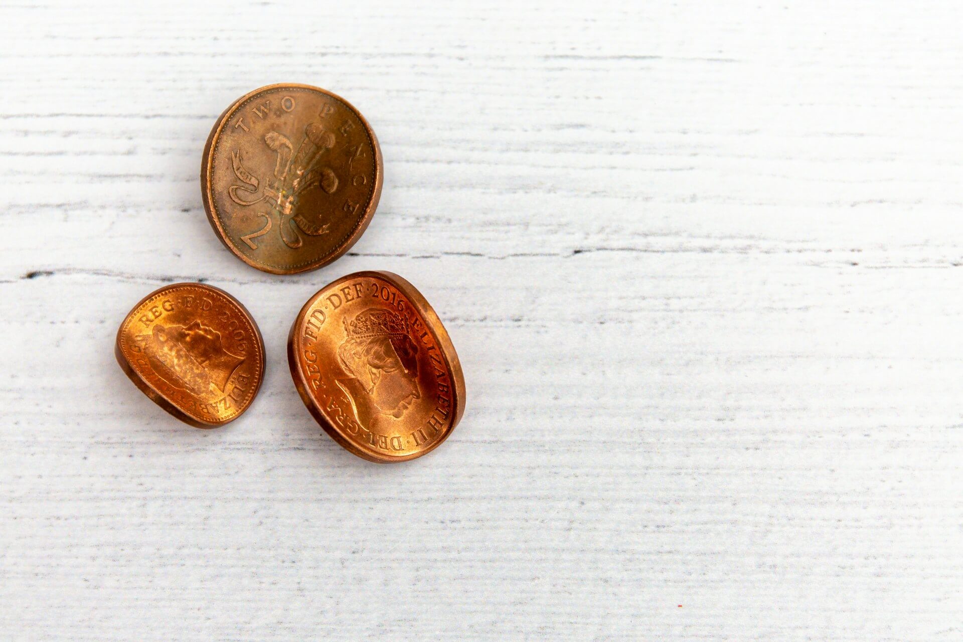 A photograph of some two pence pieces and a penny that have been bent or warped to suggest flexibility