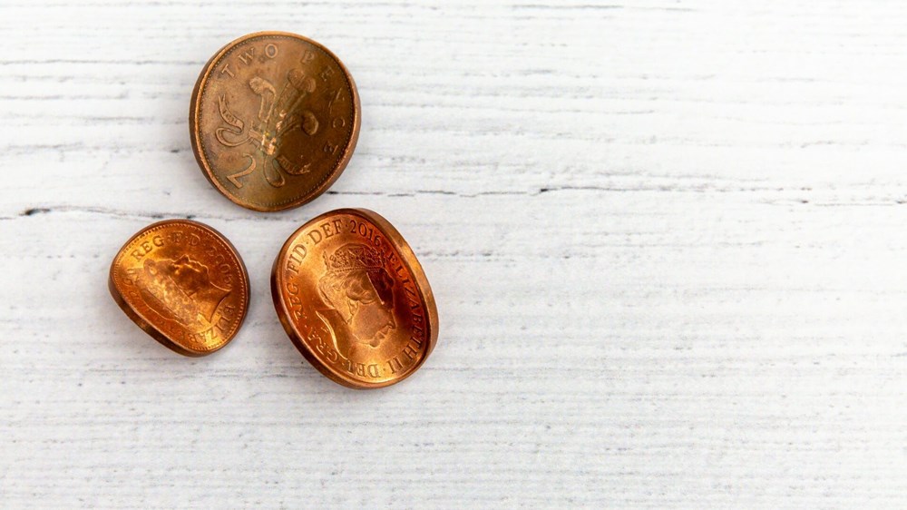 A photograph of some two pence pieces and a penny that have been bent or warped to suggest flexibility