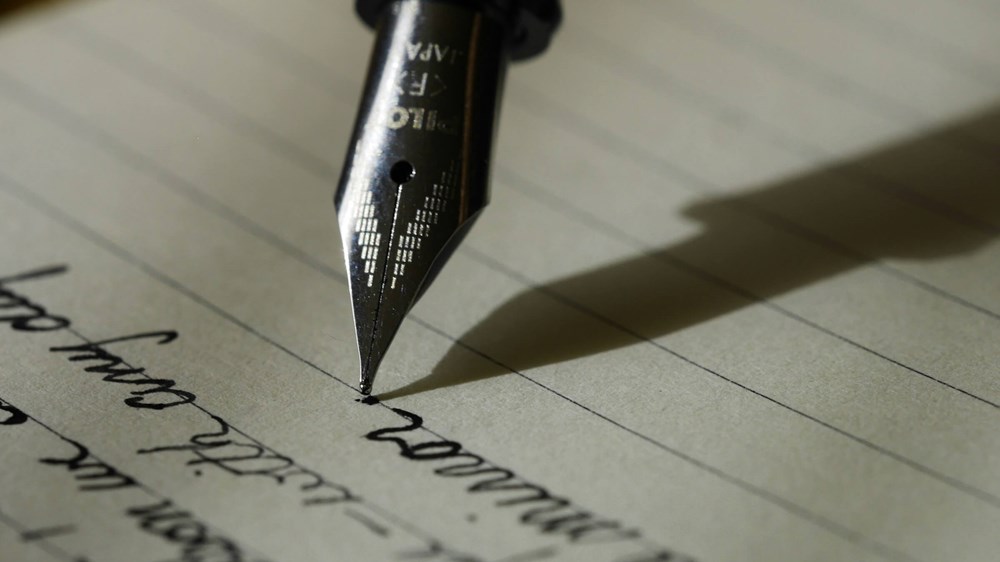 Close up photograph of a fountain pen with cursive writing.
