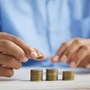 Photograph of a man wearing a blue shirt who is stacking coins into three piles