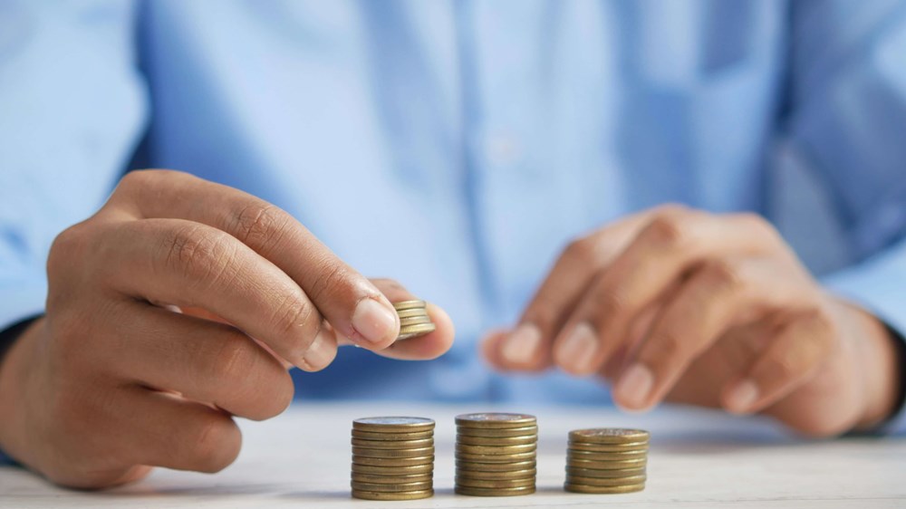 Photograph of a man wearing a blue shirt who is stacking coins into three piles