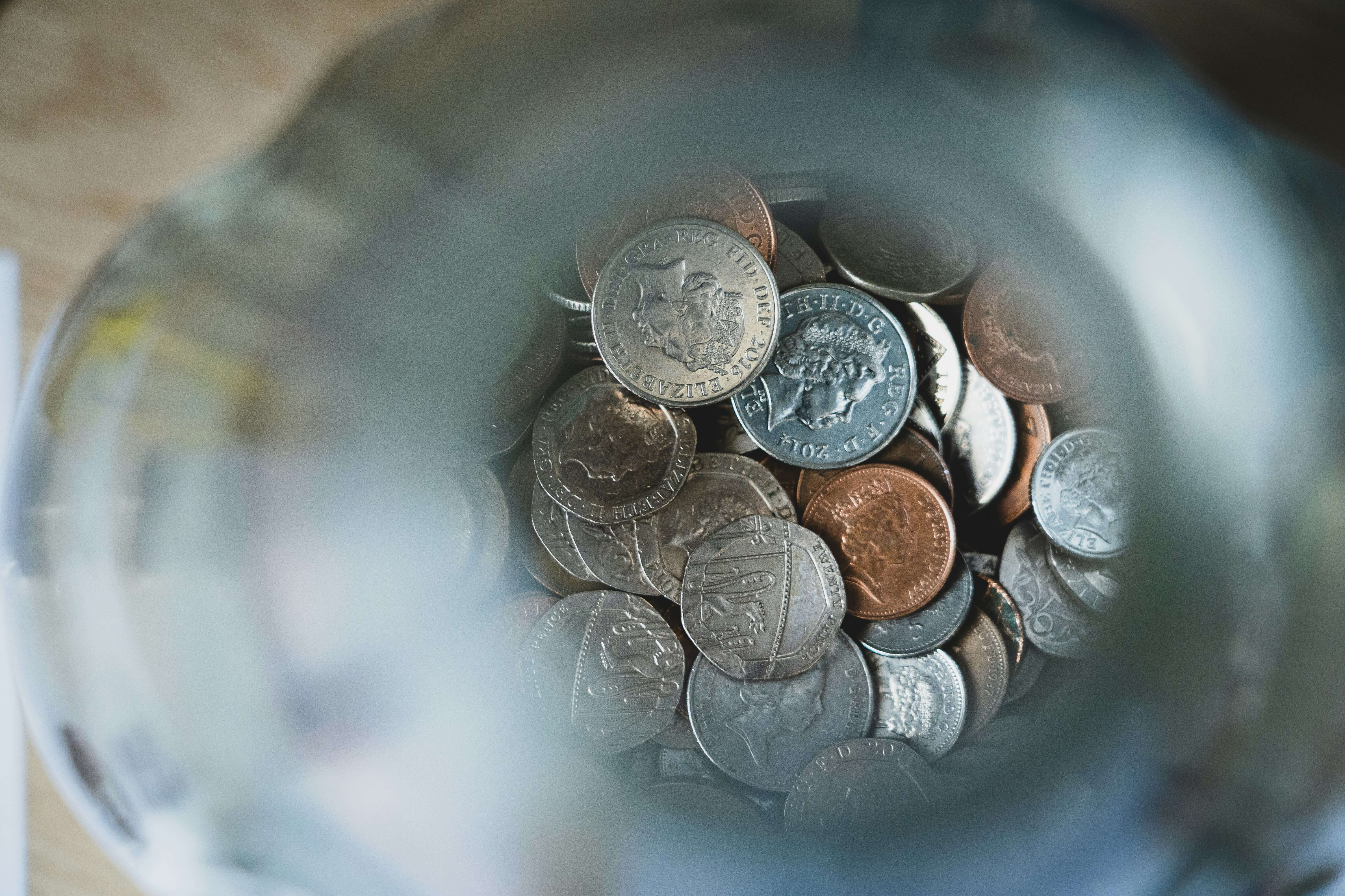 A photograph looking into a jar with a pile of coins at the bottom