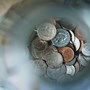 A photograph looking into a jar with a pile of coins at the bottom