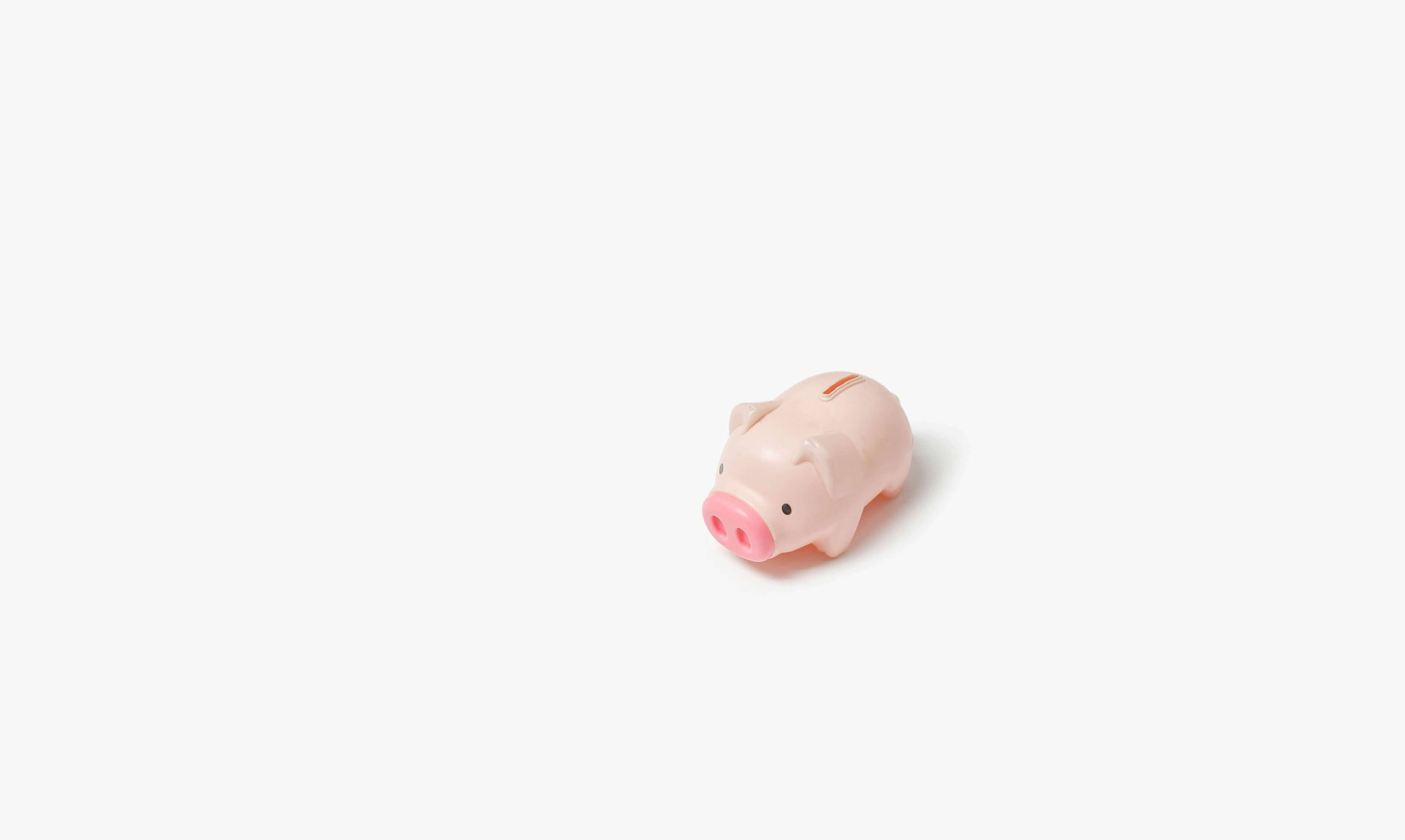 A little pink piggy bank on an off white background