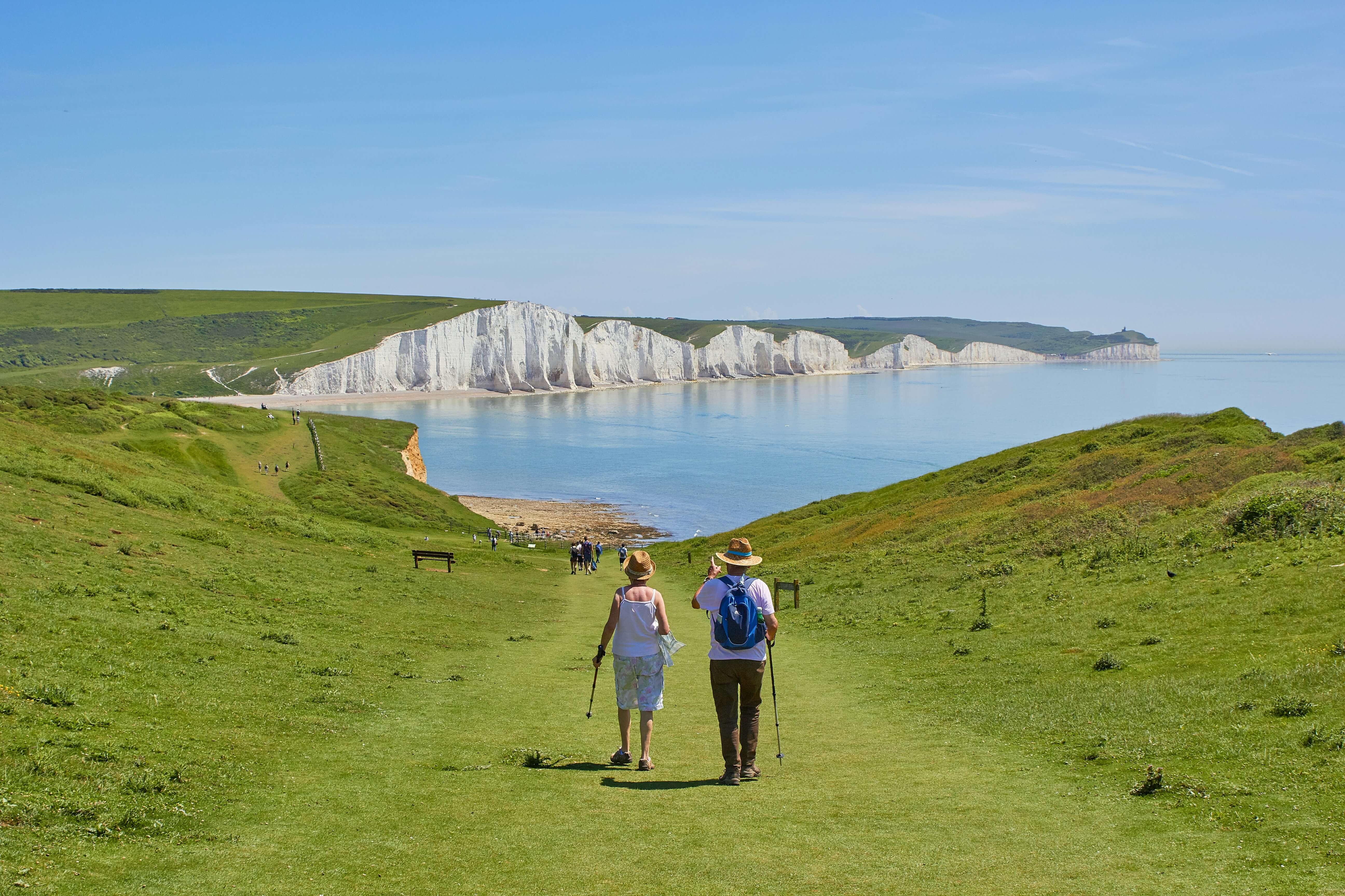 An old couple on a walk over a grassy cliff overlooking the sea