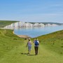 An old couple on a walk over a grassy cliff overlooking the sea 