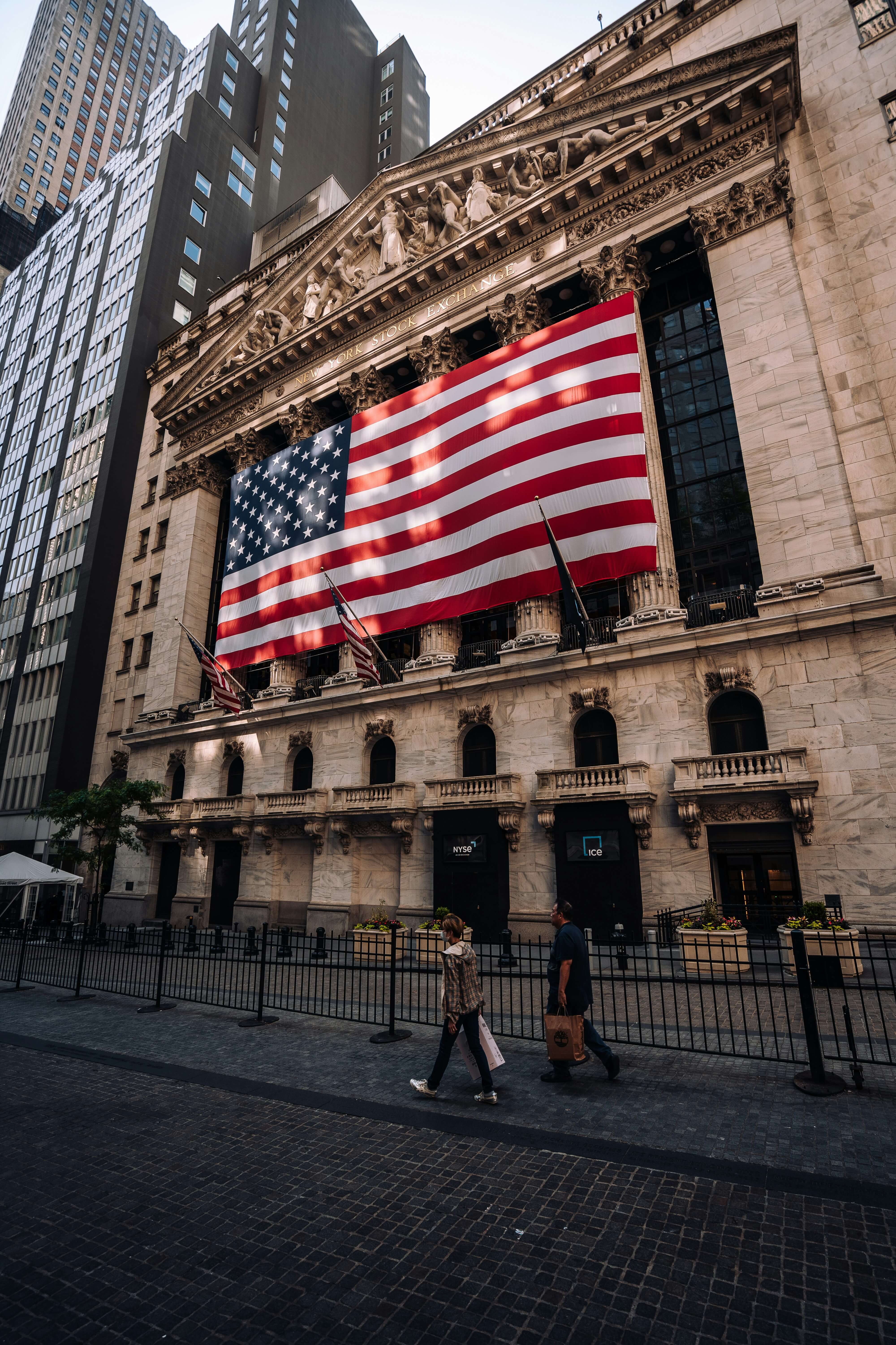 The New York Stock Exchange building with the US flag hanging over the large windows