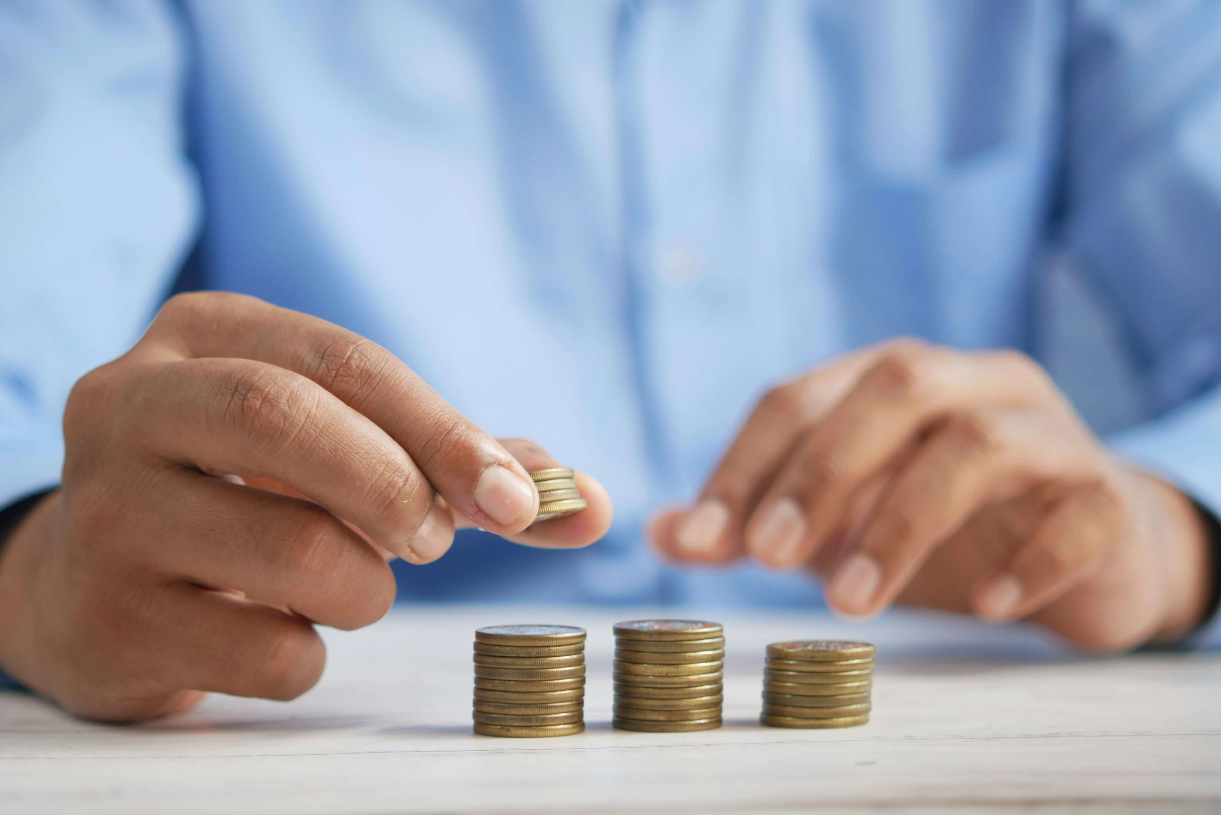 A close up of a person stacking coins into 3 piles