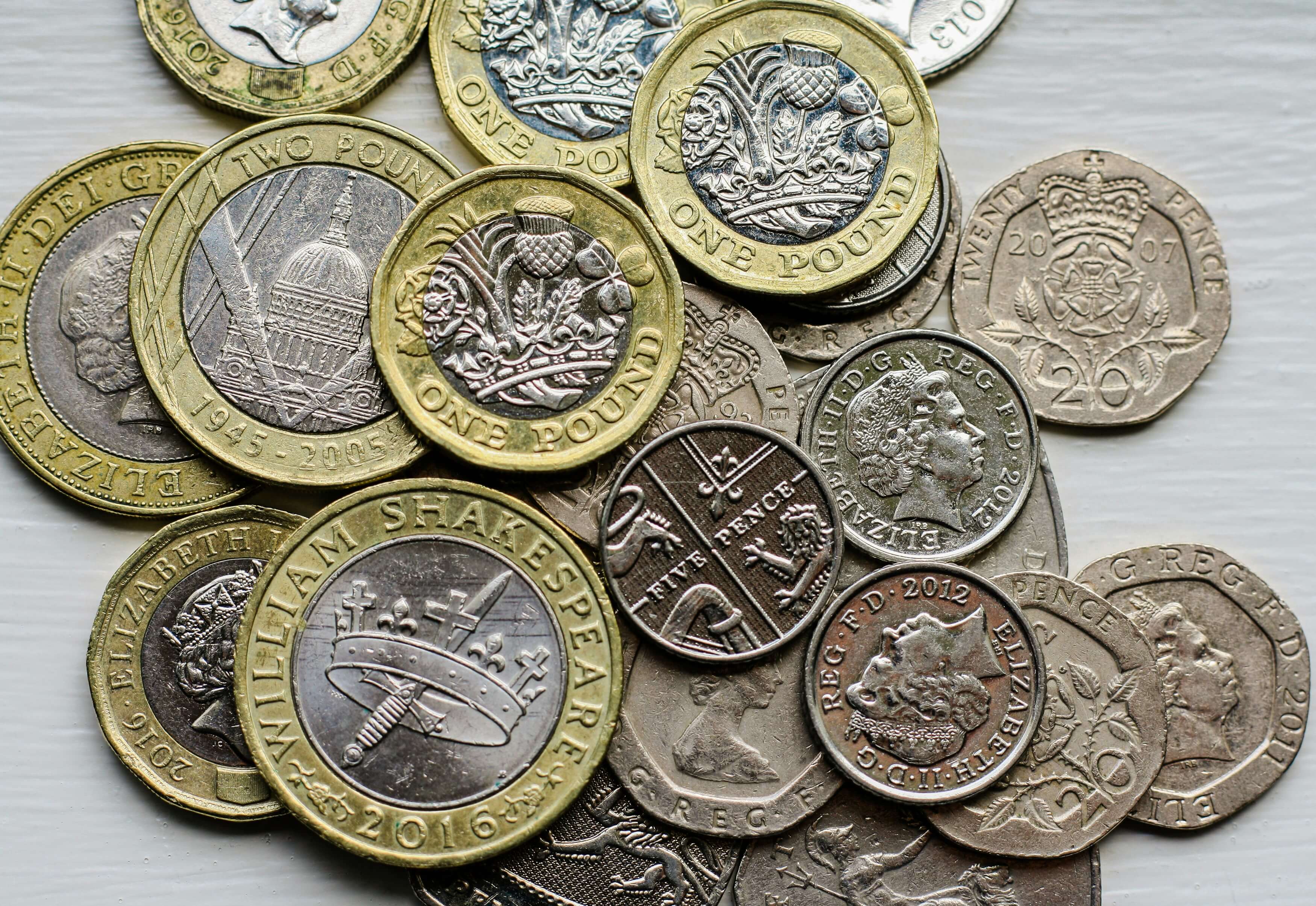 Looking down on many British coins stacked on a table