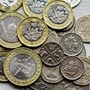 Looking down on many British coins stacked on a table 